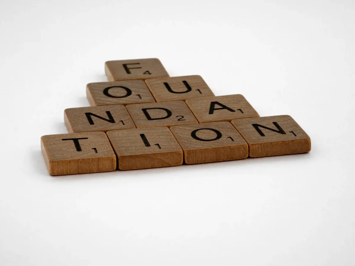 白い表面に並べられたスクラブルタイルが「Foundation（基盤）」と書かれている。