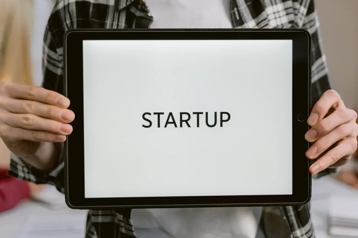 Person holding a digital tablet displaying the word 'STARTUP', representing new business concepts.